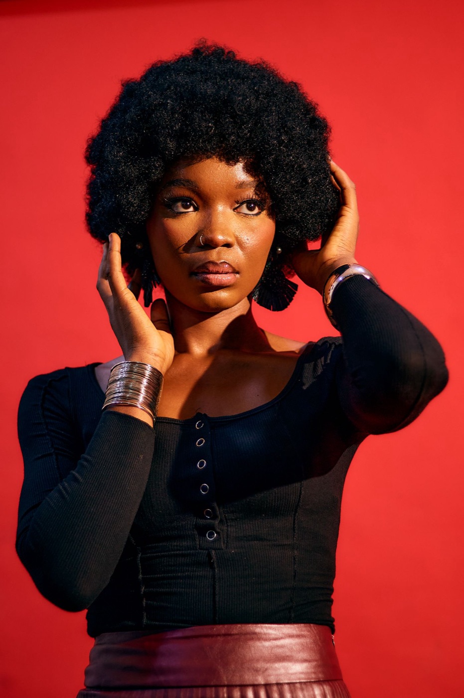Woman with curly hair against a bold red backdrop