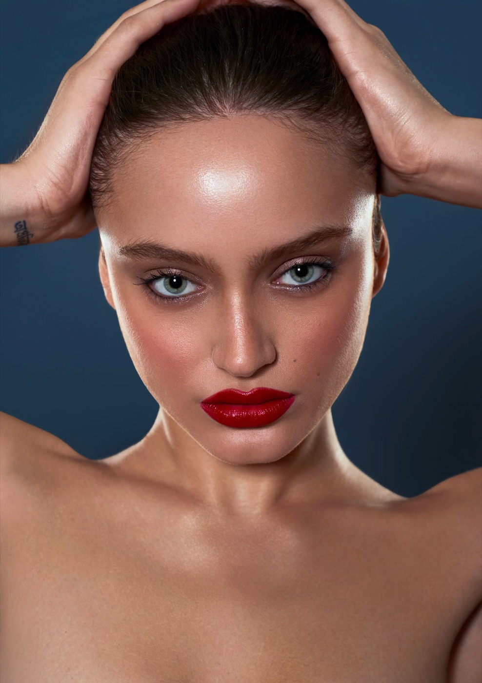 Close-up studio portrait with glowing skin on a blue background