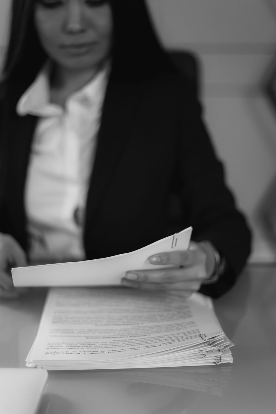 Black and white portrait of a woman in a blazer reading documents