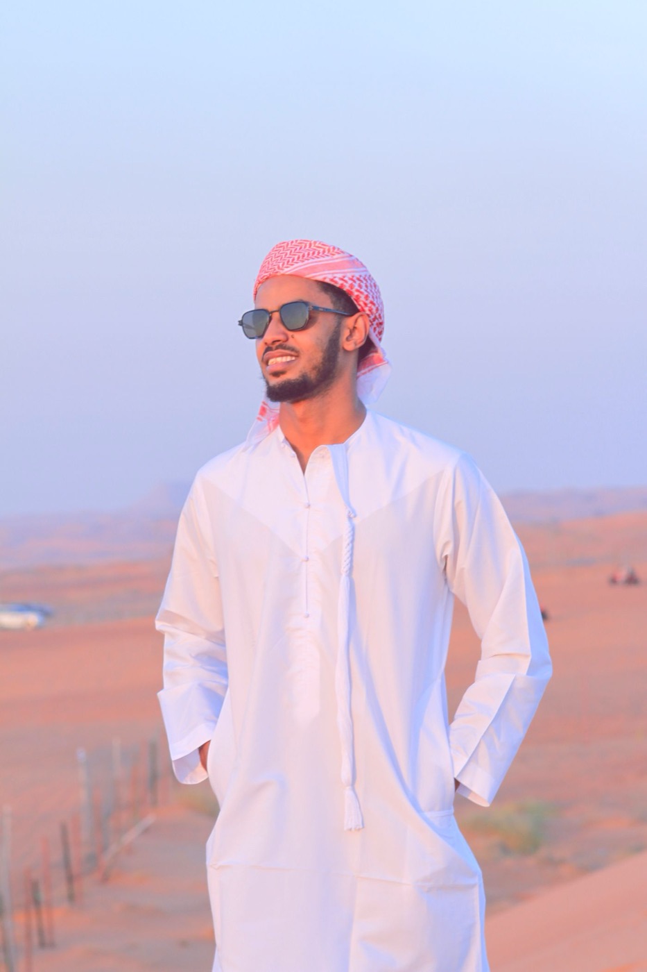 Man in a white kandura in the desert at sunset