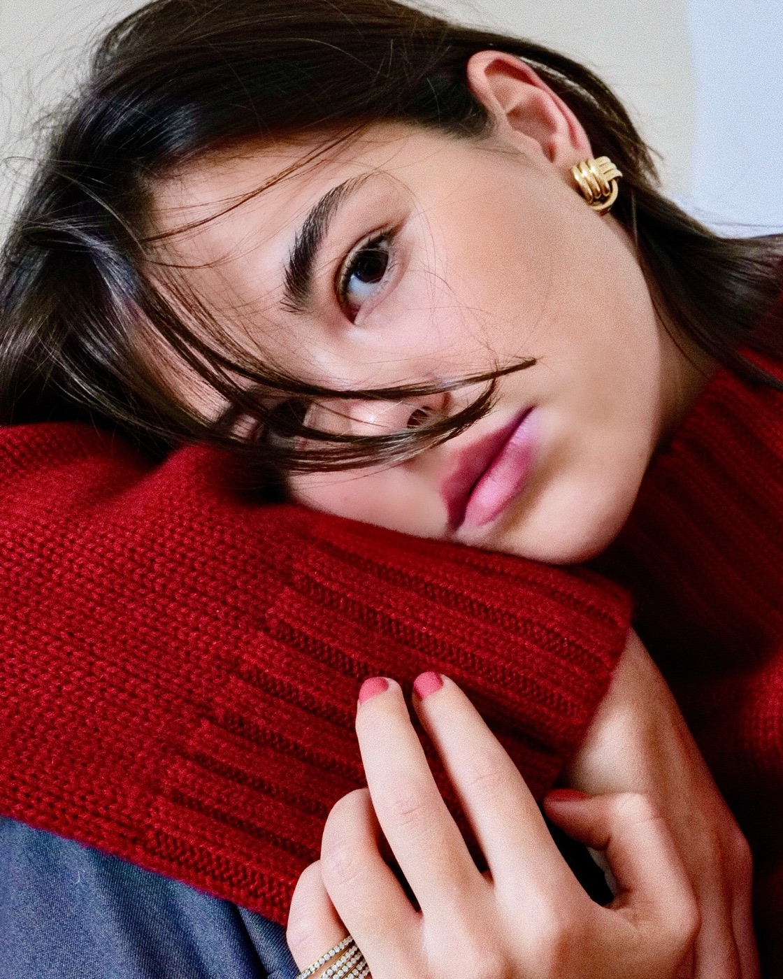 Leyl Jewels muse in a red sweater wearing gold earrings